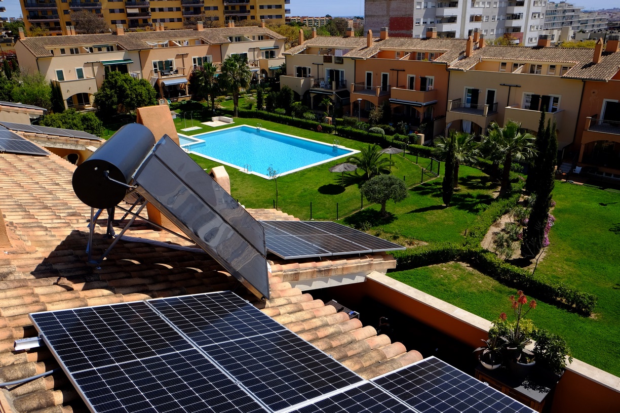 Fotografía de urbanización de casa adosadas en vista aérea donde se observan placas solares en los tejados de las casas.